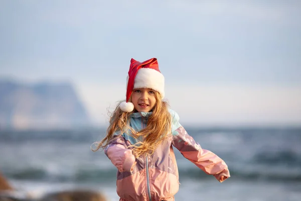 Маленькая Симпатичная Девочка Шляпе Санта Клауса Берегу Моря Ребенок Ходит — стоковое фото