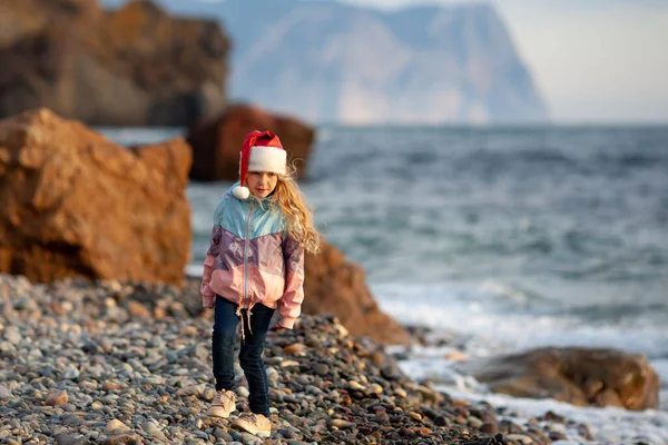 Deniz Kıyısında Noel Baba Şapkalı Küçük Güzel Kız Ceketli Bir — Stok fotoğraf