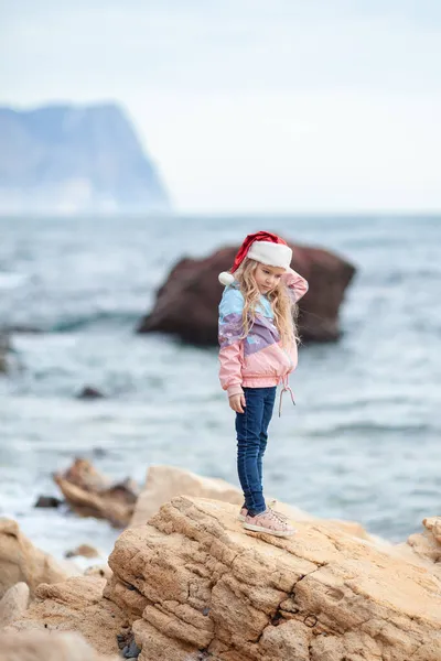 Маленькая Симпатичная Девочка Шляпе Санта Клауса Берегу Моря Ребенок Ходит — стоковое фото
