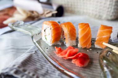 Japon suşi yemeği. Maki ve rulo ton balığı, somon, karides, yengeç ve avokado. Erimiş bir lamba şişesinden şeffaf bir tabakta servis ediliyor.