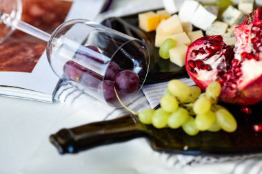 Farklı peynir ve üzümlü peynir tabağı eritilmiş bir şişeden şeffaf bir tabakta servis ediliyor.