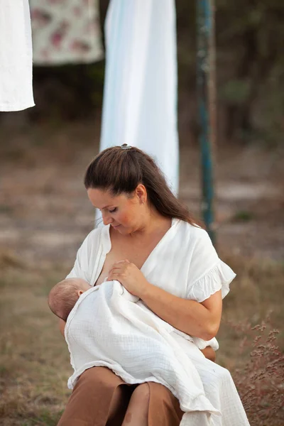 Mooie Vrouw Borstvoeding Een Baby Tegen Achtergrond Van Witte Lakens — Stockfoto