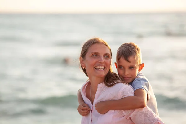 妈妈和她的儿子拥抱在一起 微笑着看着蓝色的海景 — 图库照片