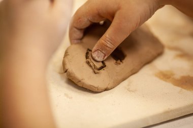 Çömlek atölyesinde, el sanatları ve kil sanatı, çocuk yaratıcı aktiviteler, sanat eğitimi gibi konularda modellik yapan sevimli bir çocuk.