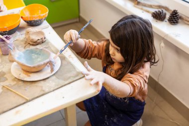 Çömlek atölyesinde, el sanatları ve kil sanatı, çocuk yaratıcı aktiviteler, sanat eğitimi gibi konularda modellik yapan sevimli bir çocuk.