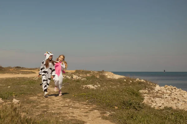 Kigurumi Ineğiyle Iki Güzel Kız Tek Boynuzlu Deniz Kıyısında Yürüyor — Stok fotoğraf
