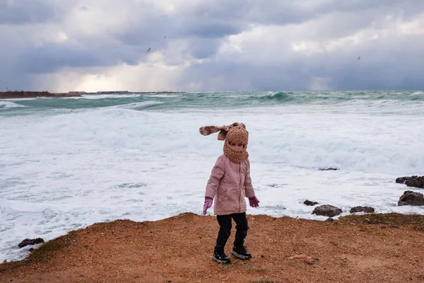 一个穿着时髦针织巴拉克拉瓦的女孩走在冬季的海滨 穿夹克的孩子 — 图库照片