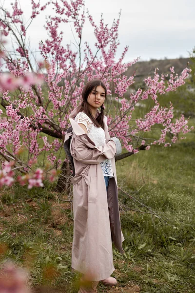 春の桃園のきれいな女の子 10代の若者がレインコート ジーンズを着て — ストック写真