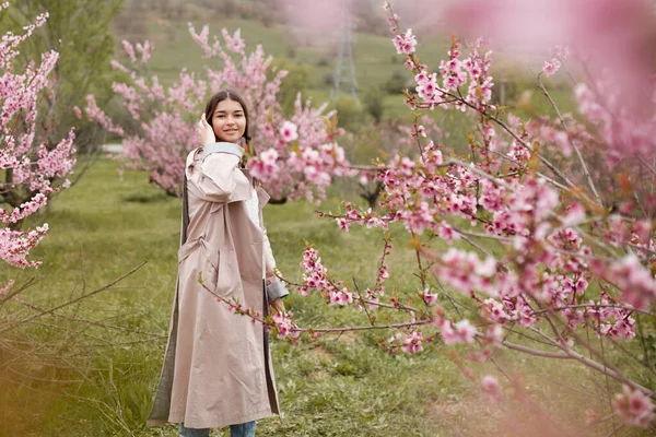 春天的桃园里 美丽的姑娘 穿着雨衣 牛仔裤的青少年 — 图库照片