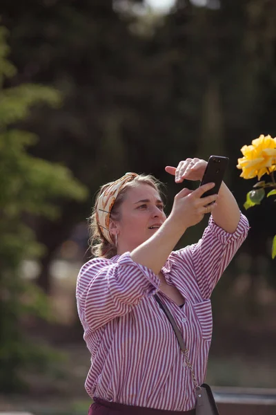 Piękna Dziewczyna Robi Zdjęcie Żółtej Róży Smartfonie — Zdjęcie stockowe