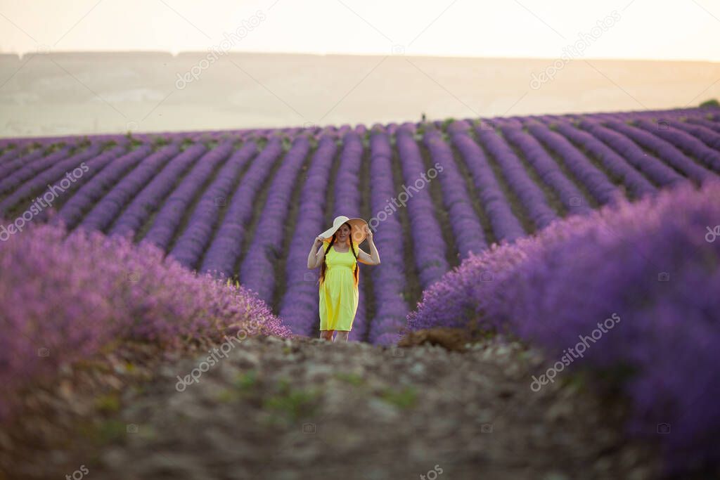 pregnant Woman in lavender flowers field at sunset in yellow dress.