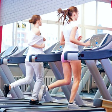 makine üzerinde çalışan iki genç sportif kadın