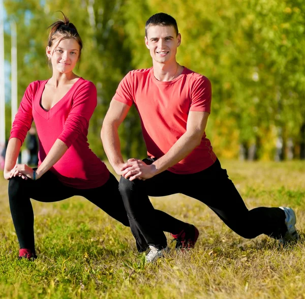Mand og kvinde kvinde laver yoga i parken - Stock-foto
