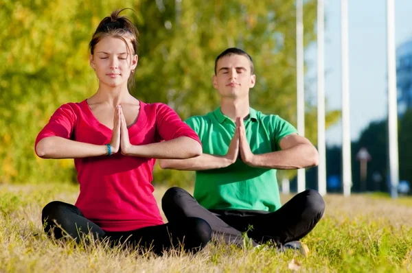 Homme et femme faisant du yoga dans le parc — Photo