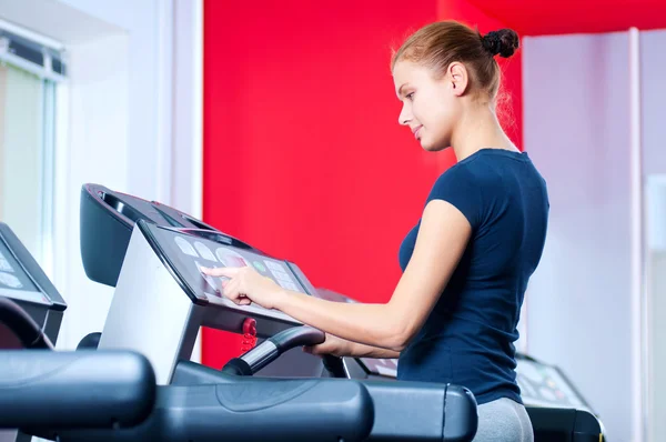 Jeune femme à la salle de gym courir sur une machine — Photo