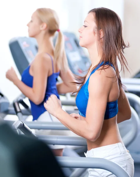 两名年轻妇女在健身房里的机器上运行 — 图库照片