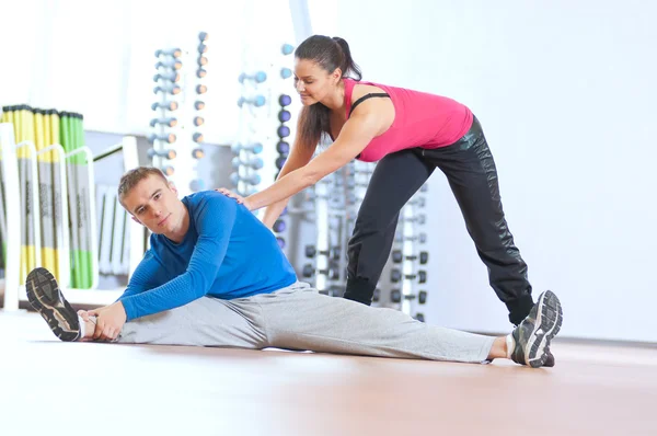 Hombre y mujer en el gimnasio haciendo estiramiento —  Fotos de Stock