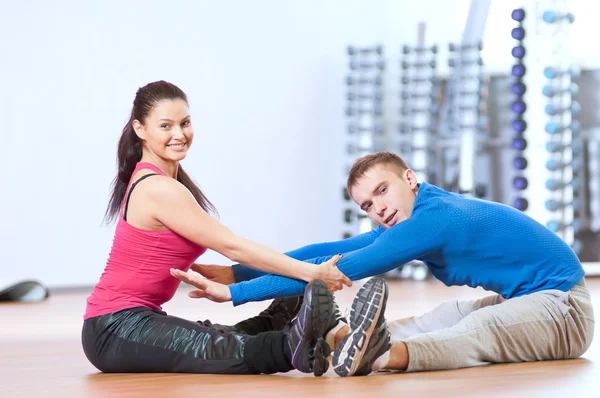 Мужчина и женщина в спортзале делают растяжку — стоковое фото