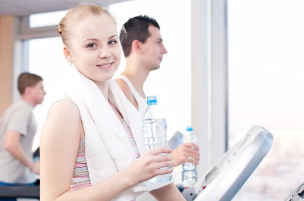 Uomo e donna che bevono acqua dopo lo sport in palestra — Foto Stock