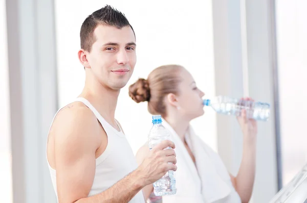 ジムでスポーツの後に男と女の飲料水 — ストック写真