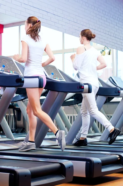 Two young sporty women run on machine — Stock Photo, Image