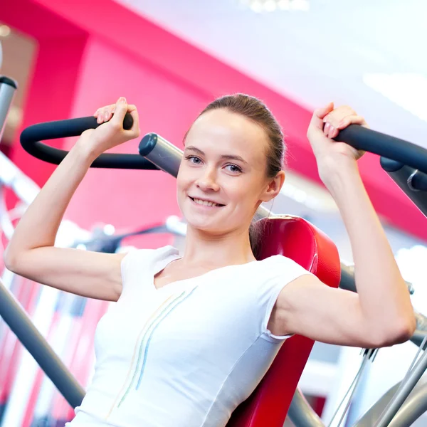 Woman doing splits on machine with weights — Stock Photo, Image