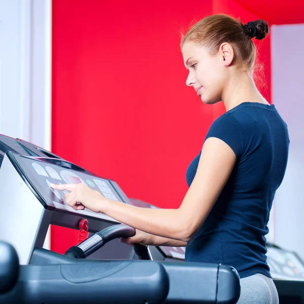 Mujer joven en el gimnasio se ejecuta en una máquina —  Fotos de Stock