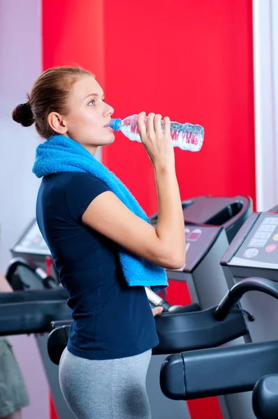 Mujer en el gimnasio bebiendo agua — Foto de Stock