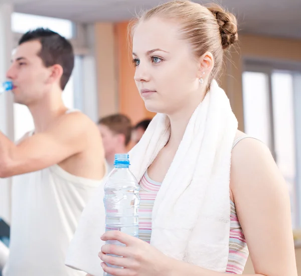 Hombre y mujer bebiendo agua después de los deportes en el gimnasio —  Fotos de Stock