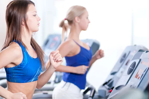 Zwei junge Frauen laufen im Fitnessstudio an einem Gerät — Stockfoto