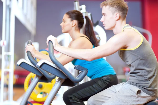 W sali gimnastycznej robi cardio trening na rowerze — Zdjęcie stockowe