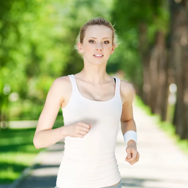 Jeune femme courant dans un parc vert — Photo