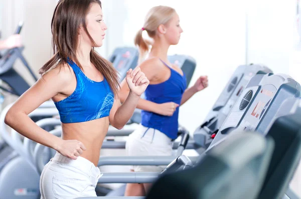 Zwei junge Frauen laufen im Fitnessstudio an einem Gerät Stockfoto