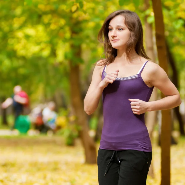 Una giovane ragazza che corre nel parco autunnale — Foto Stock