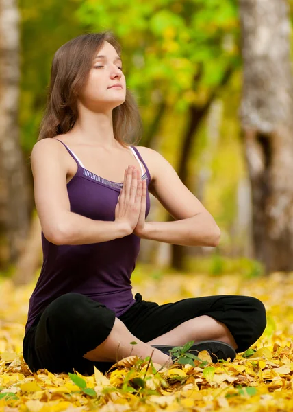 Woman doing yoga exercises in the autumn park — Stock Photo, Image