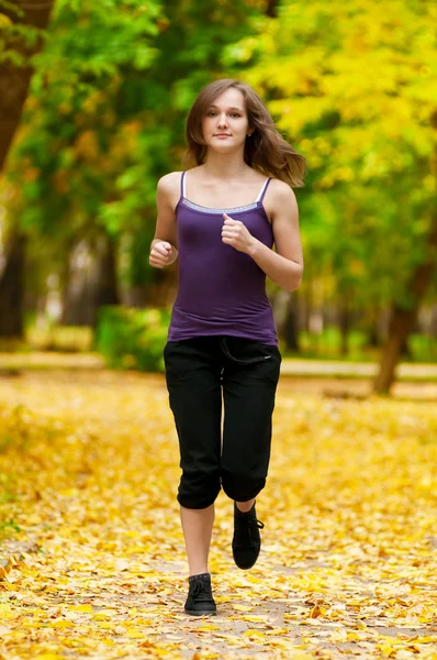 A young girl running in autumn park — Stock Photo, Image