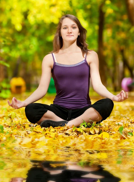 Woman doing yoga exercises in the autumn park — Stock Photo, Image