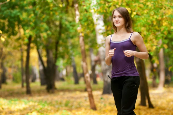 Uma jovem garota correndo no parque de outono — Fotografia de Stock