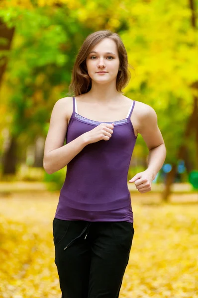 Молода дівчина біжить в осінньому парку — стокове фото