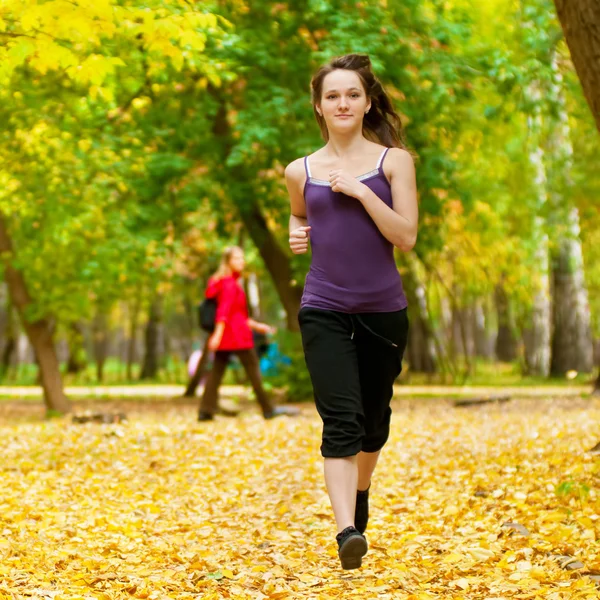 Молода дівчина біжить в осінньому парку — стокове фото