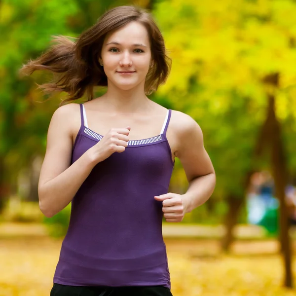 Ένα νεαρό κορίτσι που τρέχει στο πάρκο φθινόπωρο — Φωτογραφία Αρχείου