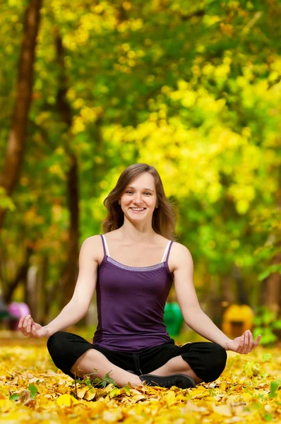 Woman doing yoga exercises in the autumn park — Stock Photo, Image