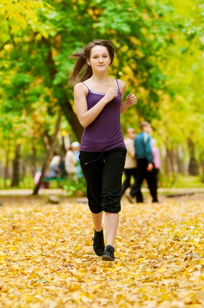 Ein junges Mädchen läuft im Herbstpark — Stockfoto