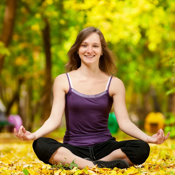 Woman doing yoga exercises in the autumn park — Stock Photo, Image