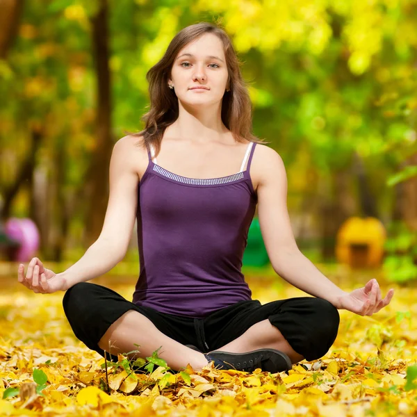 Woman doing yoga exercises in the autumn park — Stock Photo, Image