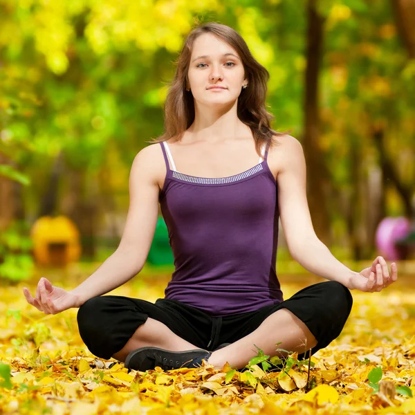 Woman doing yoga exercises in the autumn park — Stock Photo, Image