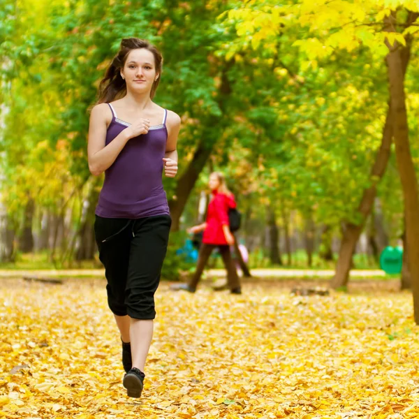 Una giovane ragazza che corre nel parco autunnale — Foto Stock