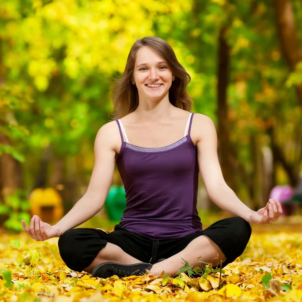 Woman doing yoga exercises in the autumn park — Stock Photo, Image