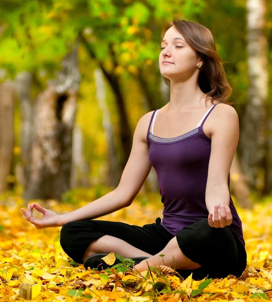 Woman doing yoga exercises in the autumn park — Stock Photo, Image