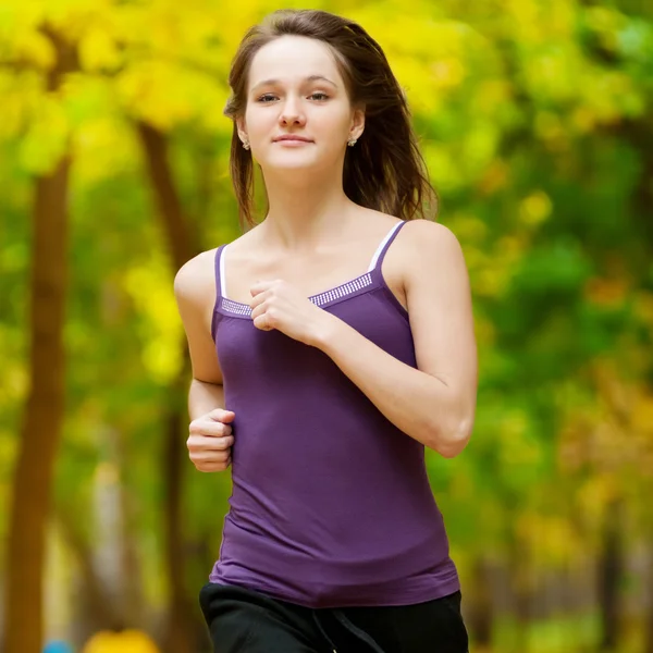 Una giovane ragazza che corre nel parco autunnale — Foto Stock